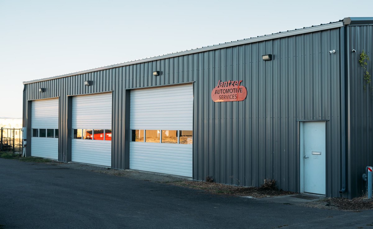 The Jantzer Automotive Services shop: a gray steel building with three white roll-up bay doors and the red Jantzer sign